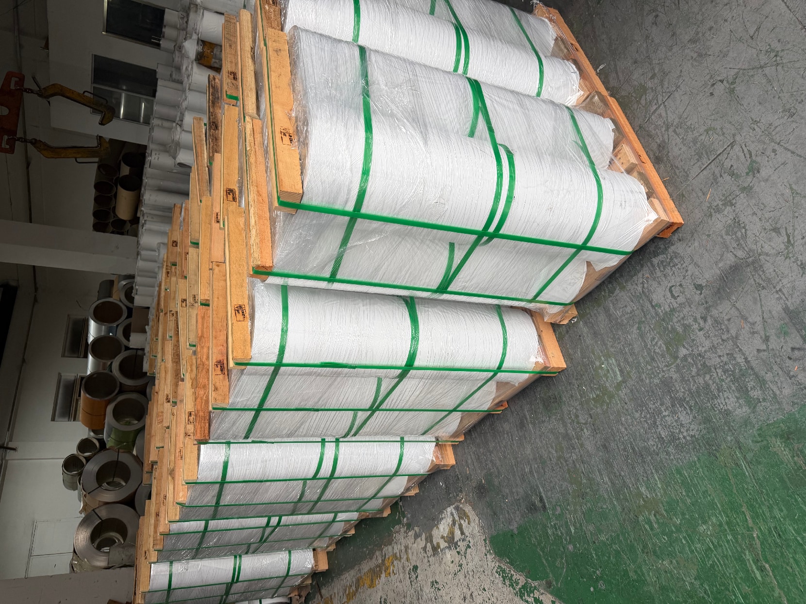 Coils wrapped in protective film and strapped to wooden pallets in the warehouse